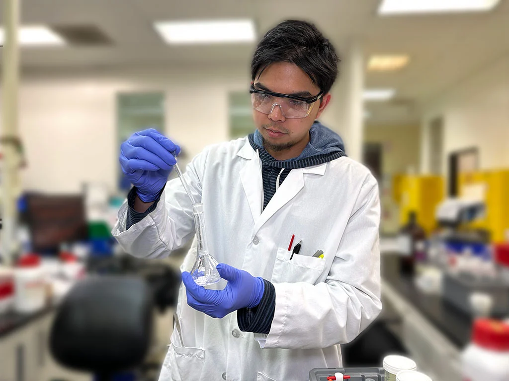 Technician in a testing laboratory preparing a sample for analytical testing.