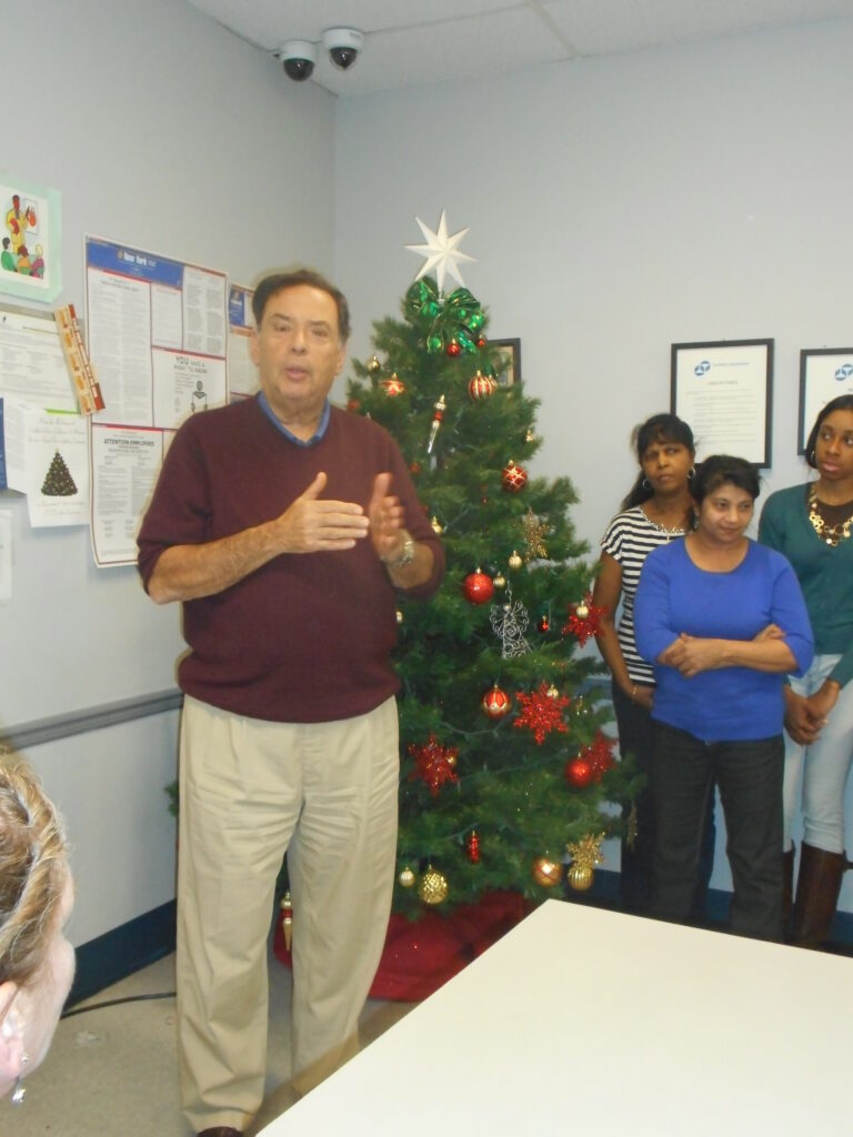 Martin Mitchell and Certified Laboratories employees standing by a Christmas tree in the lab.