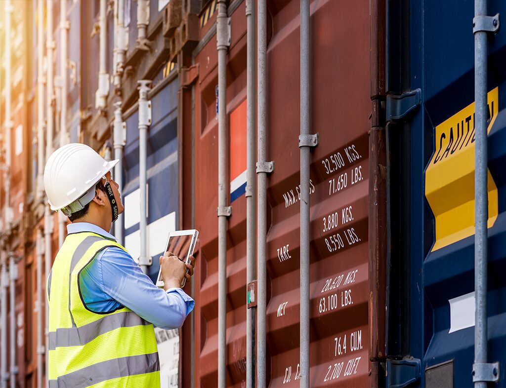 Man in protective gear inspecting shipping containers for FDA import testing.