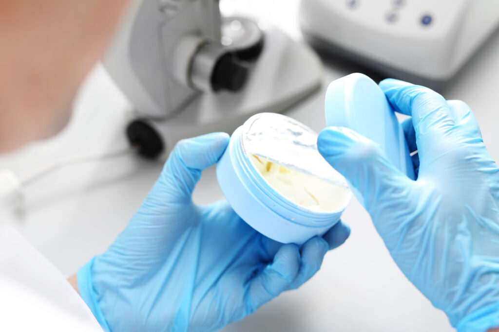 Technician in laboratory opening a container of facial cream.  