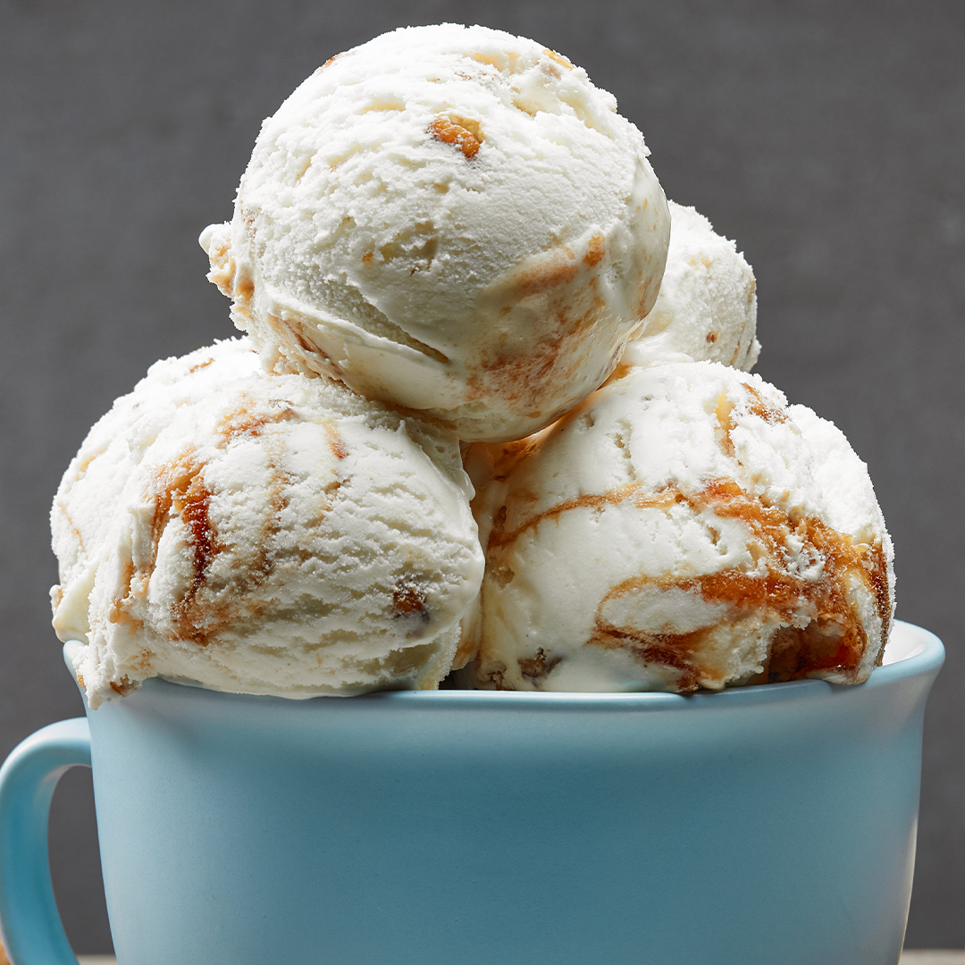 Three scoops of vanilla ice cream with caramel in a blue mug for dairy testing.