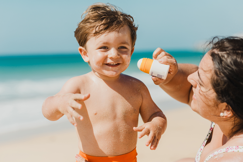 Mother applying sunscreen with bemotrizinol to toddler.